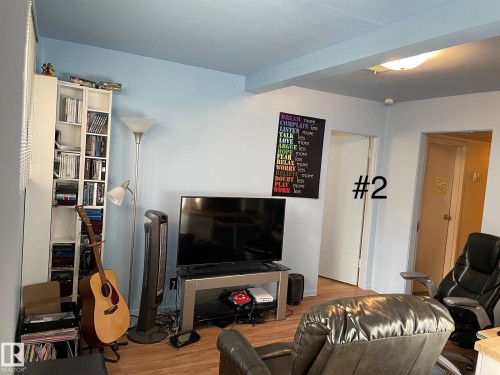 Living area featuring light blue walls, wood-finish flooring, and white trim - 10017 113 Street, Edmonton, AB 