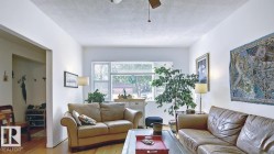 Living area with hardwood flooring, white painted walls, and a ceiling fan - 