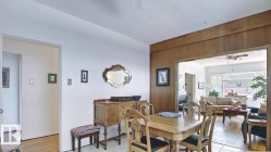 Dining area featuring wood-finish flooring, a wide entry into an adjacent living space, and wood paneling - 