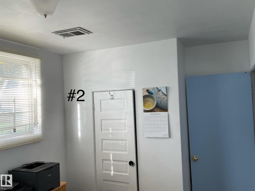 Bright interior space with a window featuring horizontal blinds, overhead light fixture, and a ceiling vent - 10017 113 Street, Edmonton, AB 
