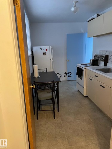 Kitchen area featuring tile flooring and a light blue interior door - 10017 113 Street, Edmonton, AB 