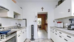 Galley kitchen featuring white cabinetry and tile countertops - 