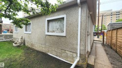 Stucco exterior with a stone-finish foundation, white window trim, white gutters, and a wood privacy fence - 