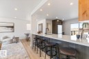 Modern kitchen featuring a white countertop island with seating, dark wood-finish cabinetry, and recessed lighting - 4508 109A Avenue, Edmonton, AB 
