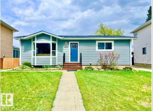 Light blue siding exterior featuring a prominent bay window with white trim, a contrasting blue entry door, and a dark shingle roof - 4508 109A Avenue, Edmonton, AB 