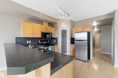 Kitchen featuring light wood cabinetry, dark countertops, and a stainless steel appliance package - 901 10504 99 Avenue, Edmonton, AB 