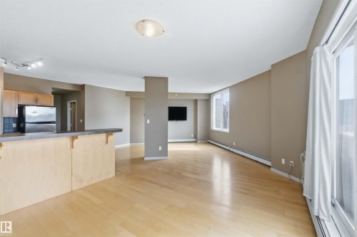 Open-concept living area featuring light wood-finish flooring, neutral wall tones, and recessed ceiling lighting - 901 10504 99 Avenue, Edmonton, AB 
