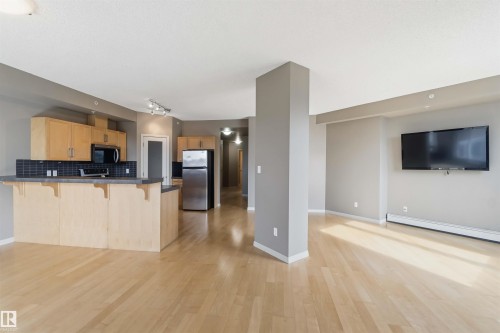 Open concept living area featuring light wood-finish flooring, a contemporary kitchen, and a neutral color palette - 901 10504 99 Avenue, Edmonton, AB 