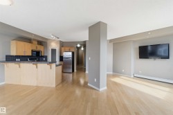 Open concept living area featuring light wood-finish flooring, a contemporary kitchen, and a neutral color palette - 