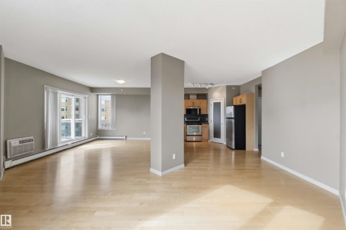 Open-concept living space featuring wood-finish flooring and neutral gray walls - 901 10504 99 Avenue, Edmonton, AB 
