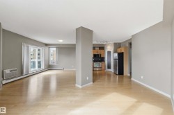 Open-concept living space featuring wood-finish flooring and neutral gray walls - 