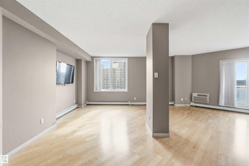 Expansive living space featuring wood-finish flooring, neutral wall tones, and abundant natural light from large windows - 901 10504 99 Avenue, Edmonton, AB 