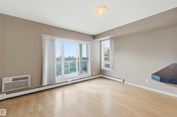Open-concept interior featuring wood-finish flooring, a large balcony with glass railing, and a built-in air conditioning unit - 
