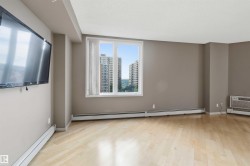 Spacious room featuring wood-finish flooring, neutral-toned walls, and a large window with vertical blinds - 