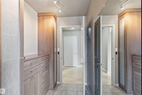 Custom built-in wood-finish cabinetry with drawers, featuring track lighting and a full-length mirrored door - 901 10504 99 Avenue, Edmonton, AB 