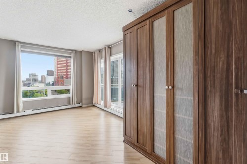 Built-in wood-finish cabinetry featuring frosted glass panels, light wood-finish flooring, a large picture window, and a sliding glass door - 901 10504 99 Avenue, Edmonton, AB 