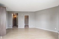 Spacious room featuring light wood-finish flooring, neutral gray walls, and white baseboards - 