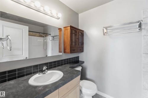 Bathroom vanity featuring a drop-in sink, dark countertop, and black tile backsplash - 901 10504 99 Avenue, Edmonton, AB 