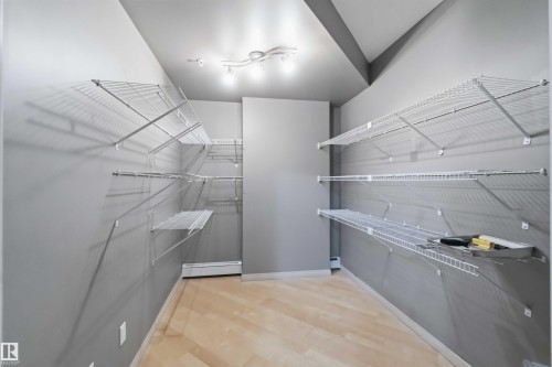 Spacious walk-in closet featuring extensive wire shelving, track lighting, light gray walls, and wood-finish flooring - 901 10504 99 Avenue, Edmonton, AB 