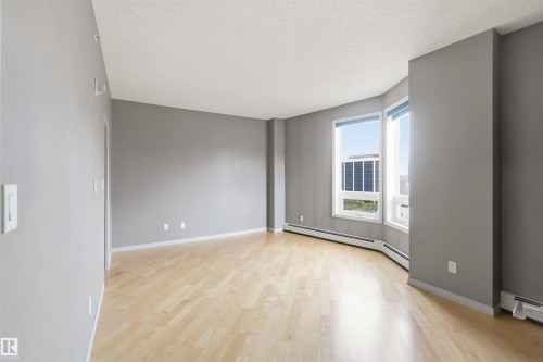 Spacious room with light wood-finish flooring, neutral gray wall paint, and white trim - 901 10504 99 Avenue, Edmonton, AB 