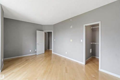 Expansive room featuring light wood-finish flooring, neutral gray wall tones, and white trim - 901 10504 99 Avenue, Edmonton, AB 