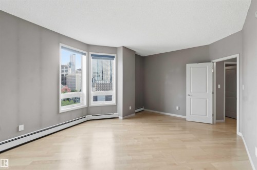 Open space featuring light wood-finish flooring, neutral gray walls, and baseboard heating - 901 10504 99 Avenue, Edmonton, AB 