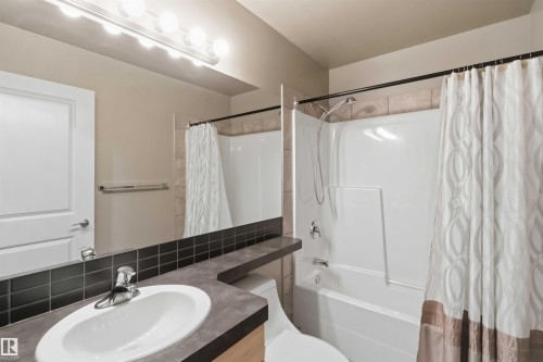 Bathroom featuring a white oval sink, dark countertop, and a full-width mirror - 901 10504 99 Avenue, Edmonton, AB 
