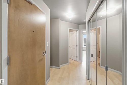 Entryway featuring a wood-finish door, light wood-finish flooring, and a mirrored closet with sliding doors - 901 10504 99 Avenue, Edmonton, AB 