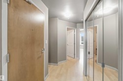 Entryway featuring a wood-finish door, light wood-finish flooring, and a mirrored closet with sliding doors - 