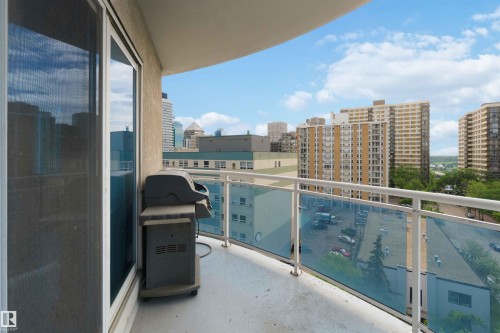 Curved balcony featuring a concrete floor, glass panel railing with white metal handrail, and floor-to-ceiling sliding glass doors - 901 10504 99 Avenue, Edmonton, AB 