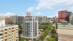 High-rise residential building with multiple balconies, glass railings, and a prominent position within an urban setting - 