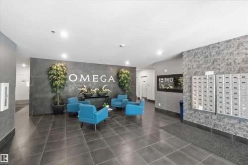 Building lobby featuring a lounge area with four blue upholstered armchairs and a central coffee table - 901 10504 99 Avenue, Edmonton, AB 