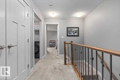 Upper-level hallway with light gray walls, carpeted flooring, and white trim - 107 Gilmore Way, Spruce Grove, AB 