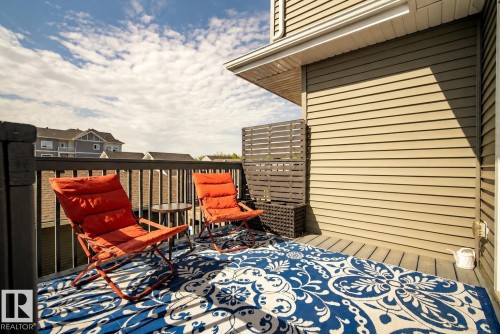 Exterior deck featuring wood-finish decking, dark railing, and a light-colored siding wall - 4013 Blackbird Link, Edmonton, AB 