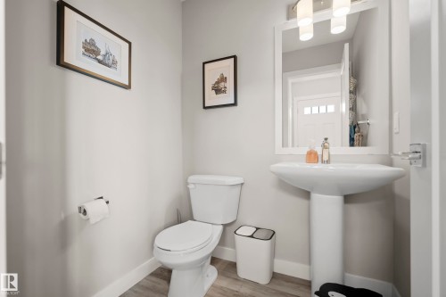 Pedestal sink with a framed mirror and a three-light vanity fixture - 4013 Blackbird Link, Edmonton, AB 