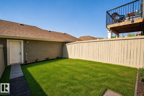 Fenced backyard featuring a manicured lawn, an exterior door, and a paver pathway - 4013 Blackbird Link, Edmonton, AB 