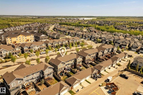 Aerial perspective showcasing a residential community with numerous detached homes and townhomes, characterized by consistent architectural styling and landscaped streets - 4013 Blackbird Link, Edmonton, AB 