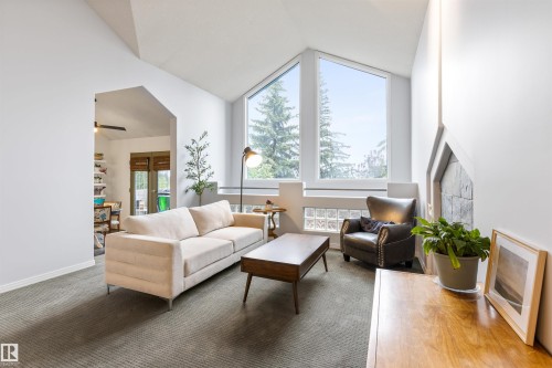 Living area featuring vaulted ceilings, oversized windows, and a stone-clad fireplace surround - 10 Everest Crescent, St. Albert, AB 