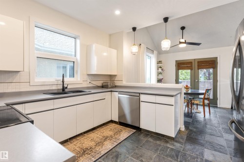 Modern kitchen featuring white flat-panel cabinetry, a black double-basin sink with a matte black faucet, and a subway tile backsplash - 10 Everest Crescent, St. Albert, AB 
