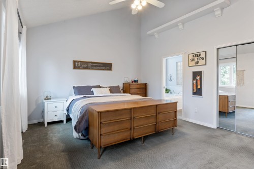 Bedroom featuring a vaulted ceiling with a ceiling fan, track lighting, and soft gray carpeting - 10 Everest Crescent, St. Albert, AB 