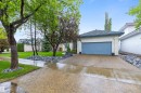 Exterior featuring a two-car garage with a blue door, stucco facade, and a dark shingled roof - 10 Everest Crescent, St. Albert, AB 