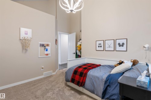 Bedroom featuring vaulted ceilings, neutral wall tones, plush carpet, white baseboards, and a contemporary ceiling fixture - 10 Everest Crescent, St. Albert, AB 