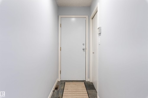 Entryway featuring a white door, light gray walls, dark tile flooring, and a textured area rug - 10 Everest Crescent, St. Albert, AB 