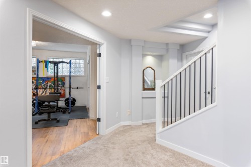 Interior hallway with carpeted flooring leading to a wood-finish floor room - 10 Everest Crescent, St. Albert, AB 