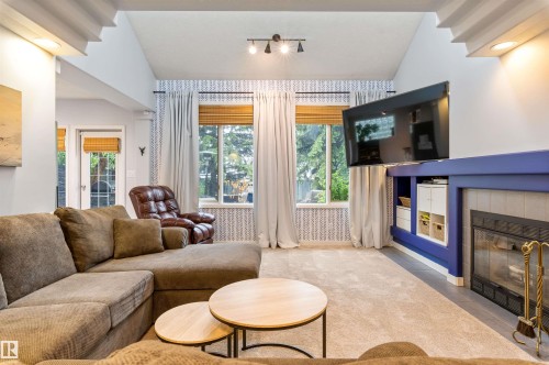 Living room featuring a fireplace with a blue mantel, built-in shelving, vaulted ceilings, and large windows - 10 Everest Crescent, St. Albert, AB 