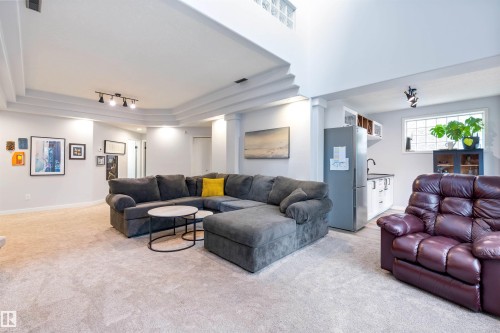 Spacious room featuring light-colored carpeting, a built-in wet bar with a refrigerator, and a window with glass block accents - 10 Everest Crescent, St. Albert, AB 