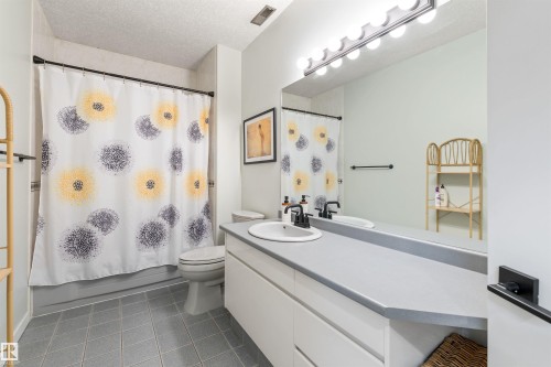 Bathroom featuring a single basin vanity with a light gray countertop, matte black faucet, and a large wall-mounted mirror - 10 Everest Crescent, St. Albert, AB 
