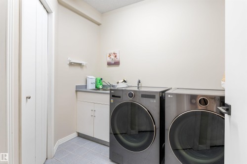 Dedicated laundry area featuring a utility sink, cabinet storage, and tile flooring - 10 Everest Crescent, St. Albert, AB 