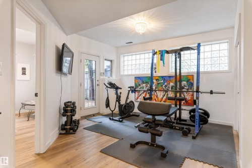 Dedicated exercise room featuring wood-finish flooring, glass block windows, and a glass-paneled exterior door - 10 Everest Crescent, St. Albert, AB 