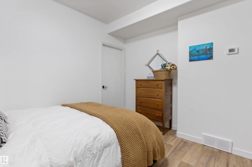 Bedroom featuring wood-finish flooring, white walls, and a white door with a black handle - 10 Everest Crescent, St. Albert, AB 